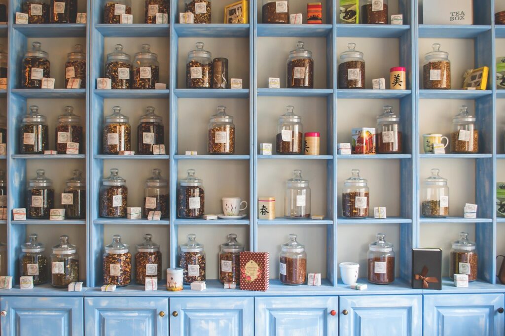 Glass jars of dried herbs on wooden shelves